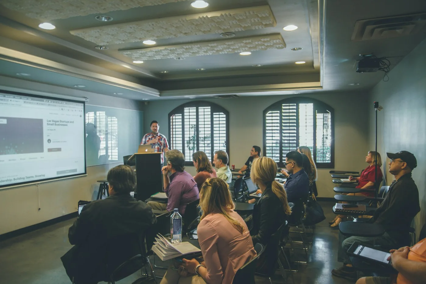 A facilitator presenting to a seated group in a training room